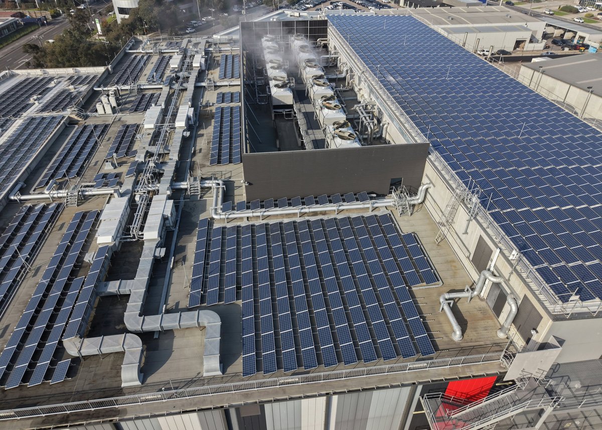 Industrial rooftop with solar panel arrays and cooling towers providing green power